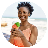 Mulher segurando sorvete na praia enquanto sorri